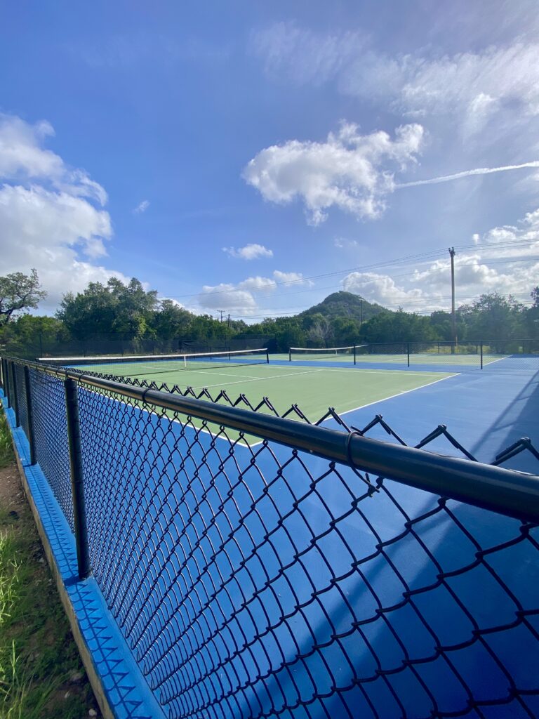 Outdoor pickleball and tennis courts at EmilyAnn Theatre & Gardens, with a rocky hill and trees visible in the background